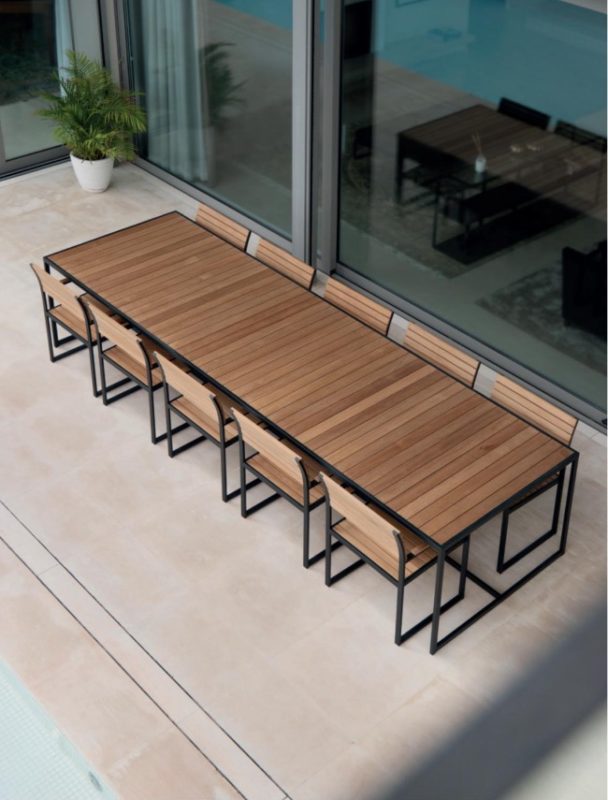 Garden Ease Dining Table — Outdoor dining table with benches on a patio, adjacent to sliding glass doors